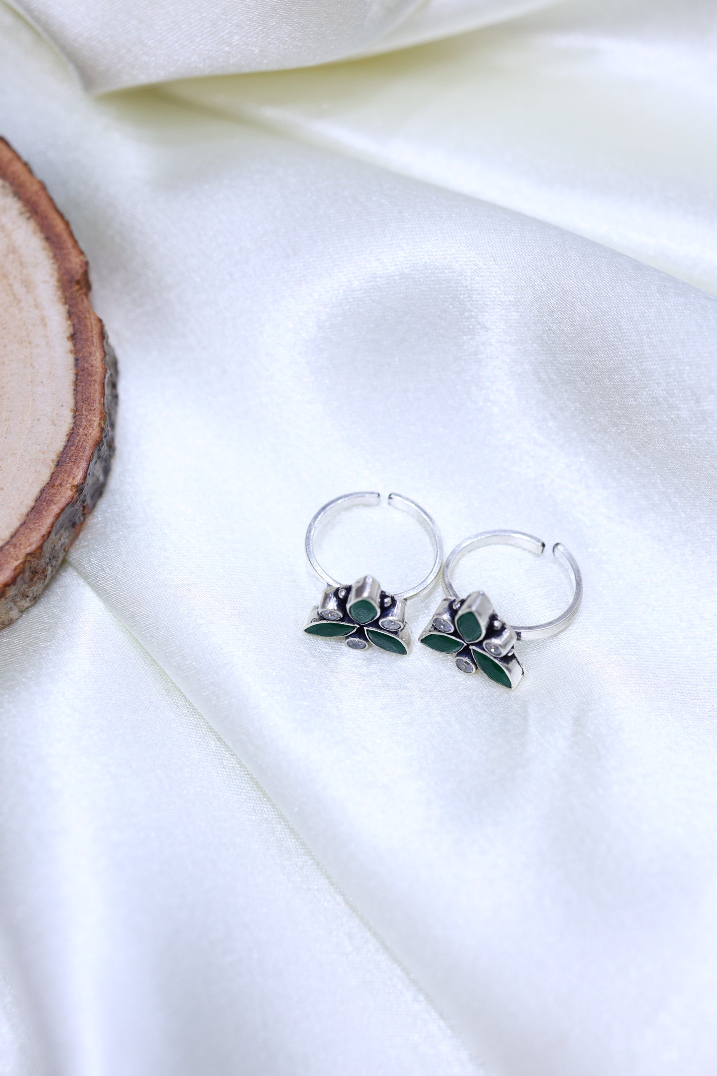 Pair of sterling silver toe rings with green leaf stone and white stones arranged in a floral triangle pattern.