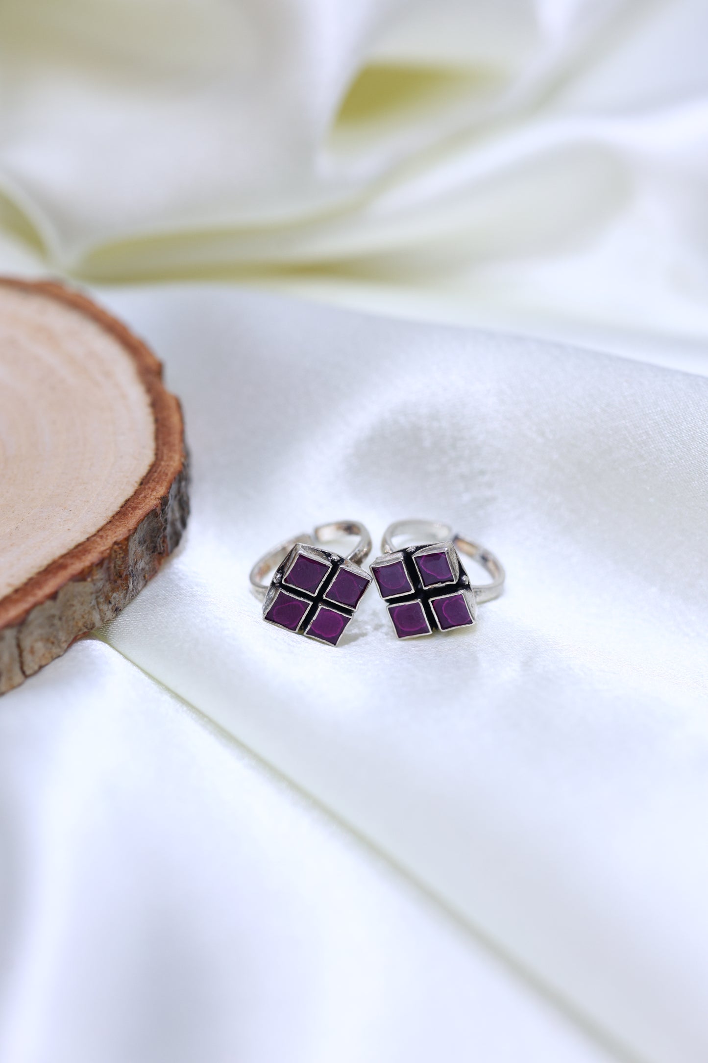 Pair of sterling silver toe rings featuring four-square purple stone design.