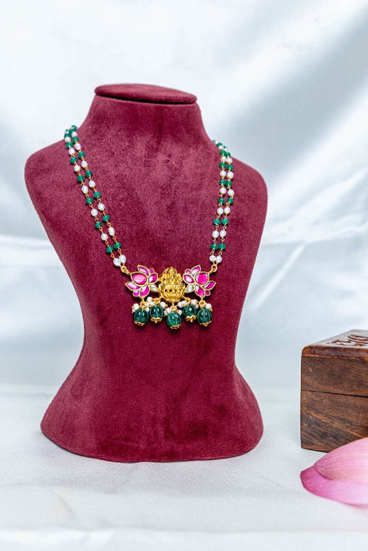 Traditional temple-style necklace with a Lakshmi pendant, pink enamel lotus motifs, pearls, and green stone beads.
