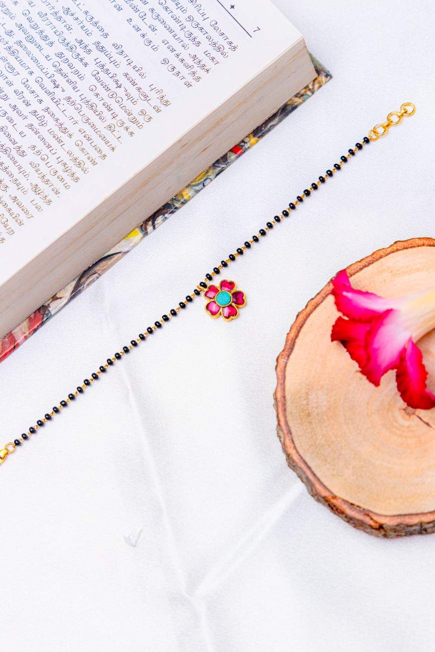 Mangalsutra bracelet with black beads and a pink–turquoise stone flower charms.