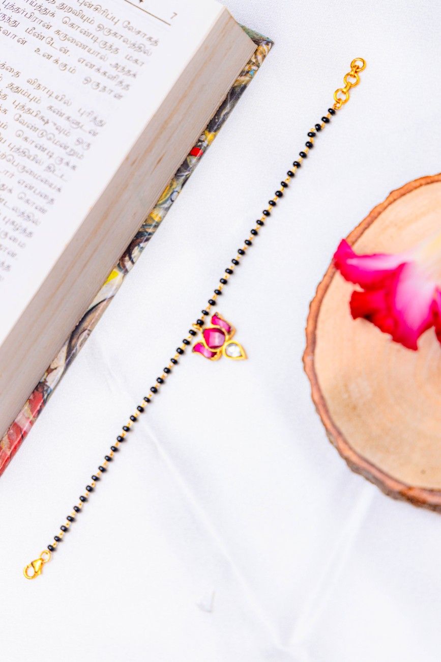 Black bead mangalsutra bracelet with pink stone lotus charm.