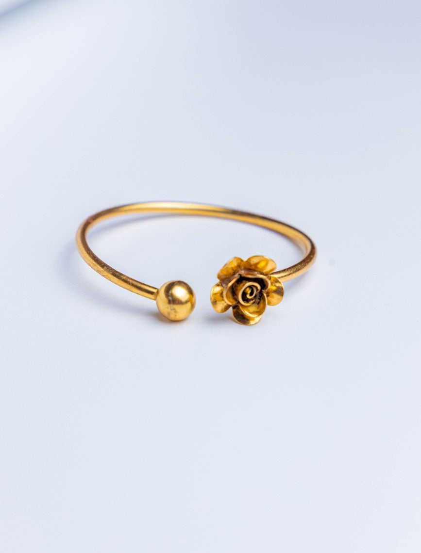 Gold bracelet with a rose charm on a light gray background