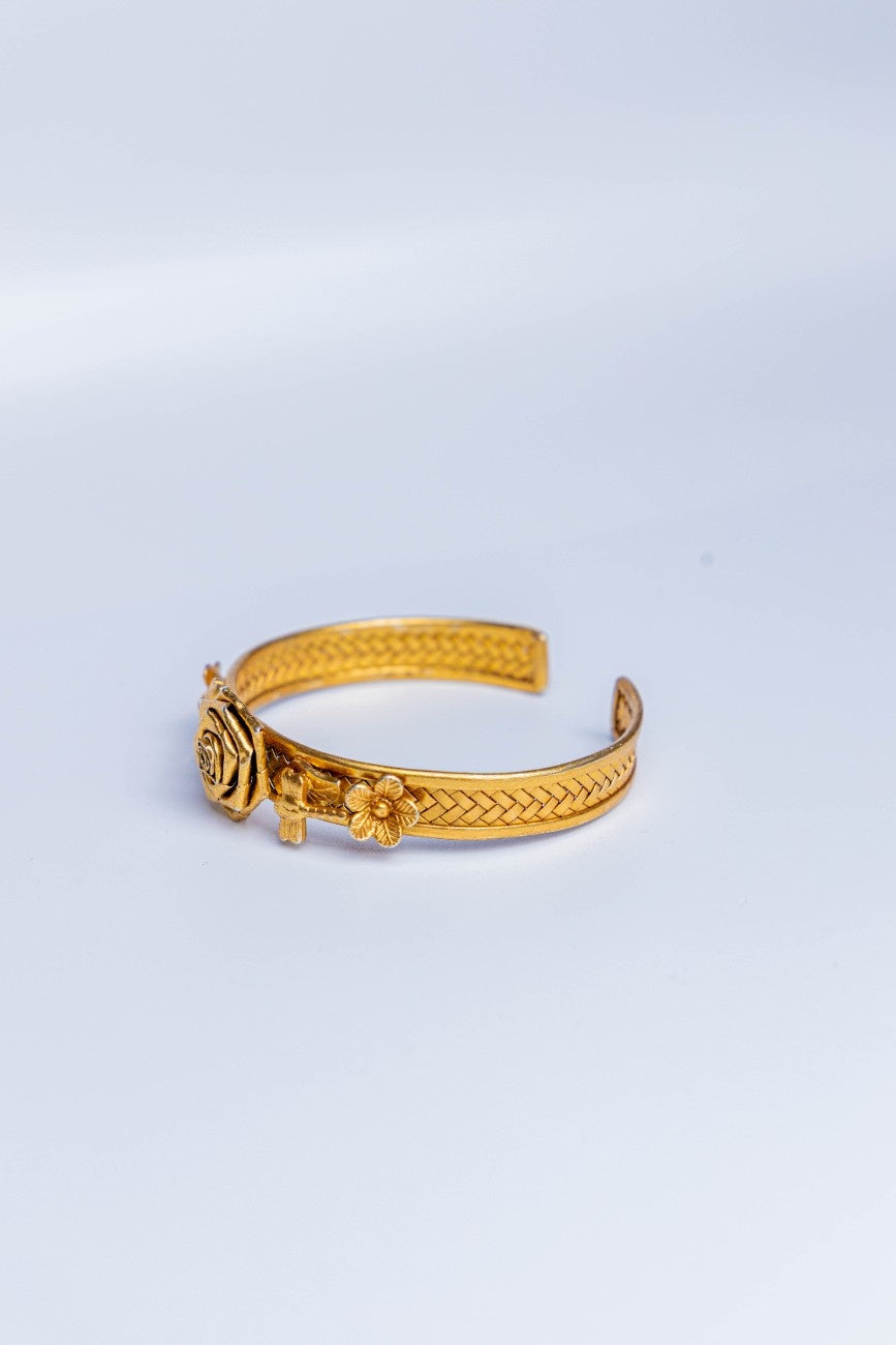 Gold bracelet with floral designs on a light gray background