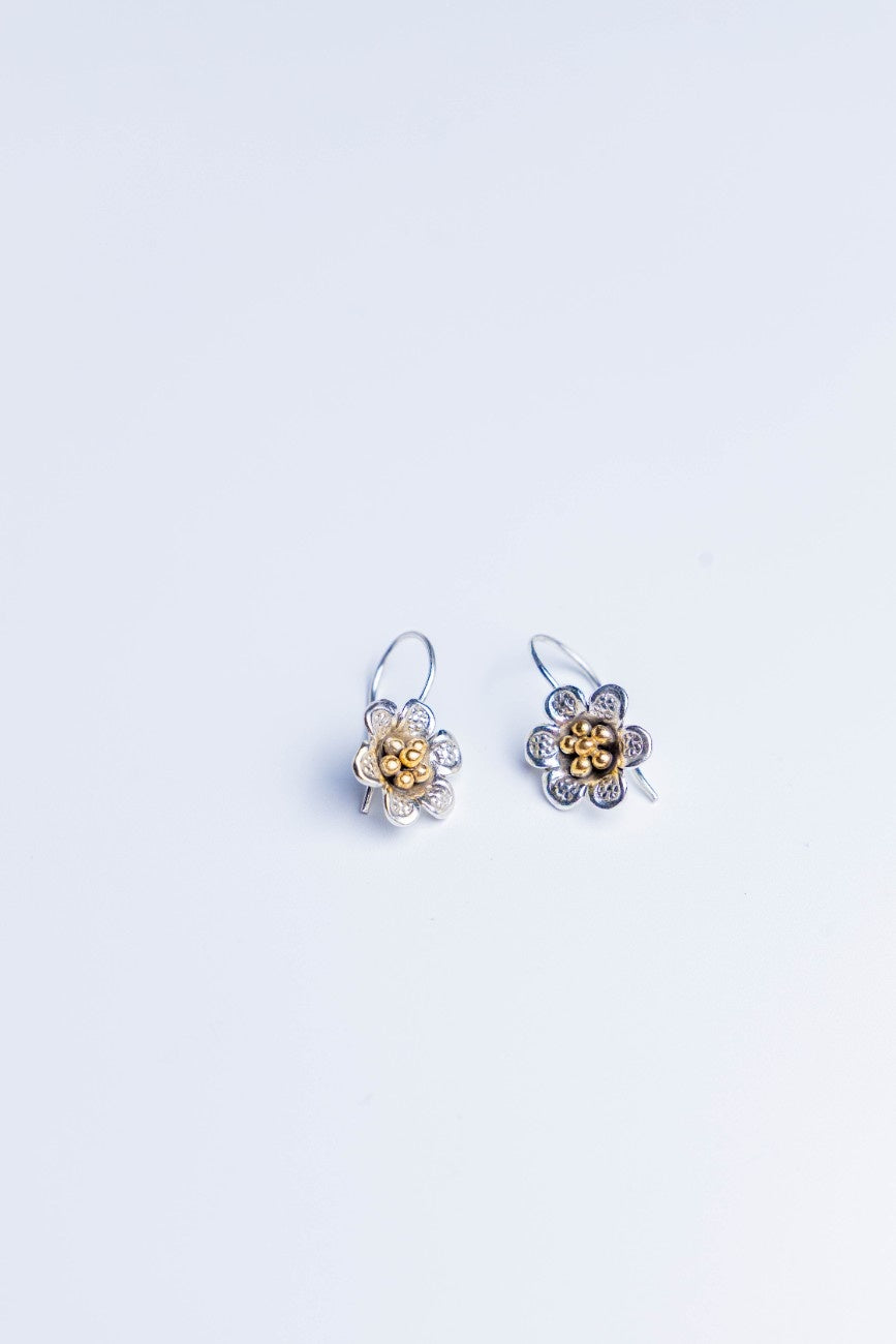 Handcrafted dual tone floral silver earrings with gold bead detailing.
