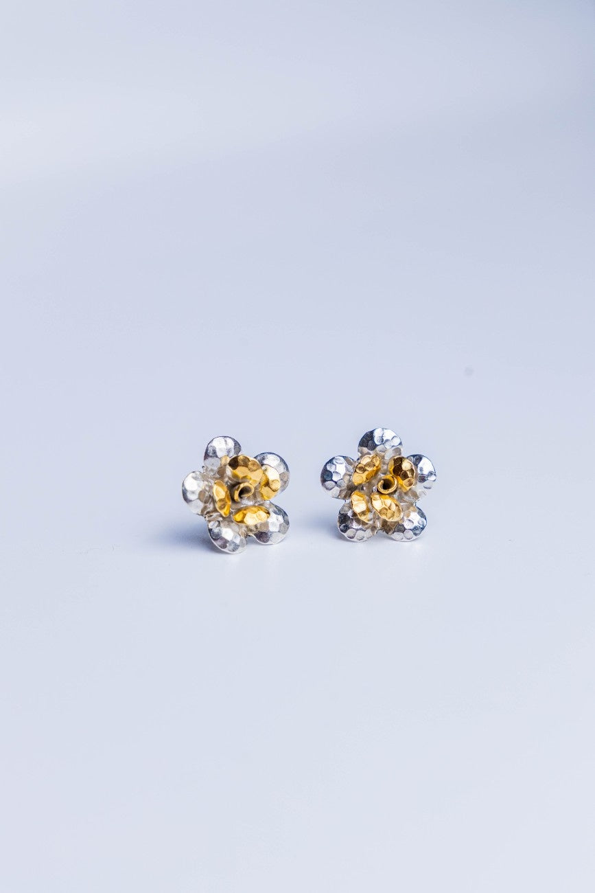 Handcrafted dual-tone sterling silver stud earrings featuring hammered petal design with gold-accented floral center.
