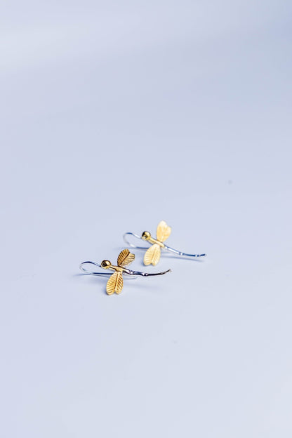 Dual-tone dragonfly earrings with golden wings and silver body placed.