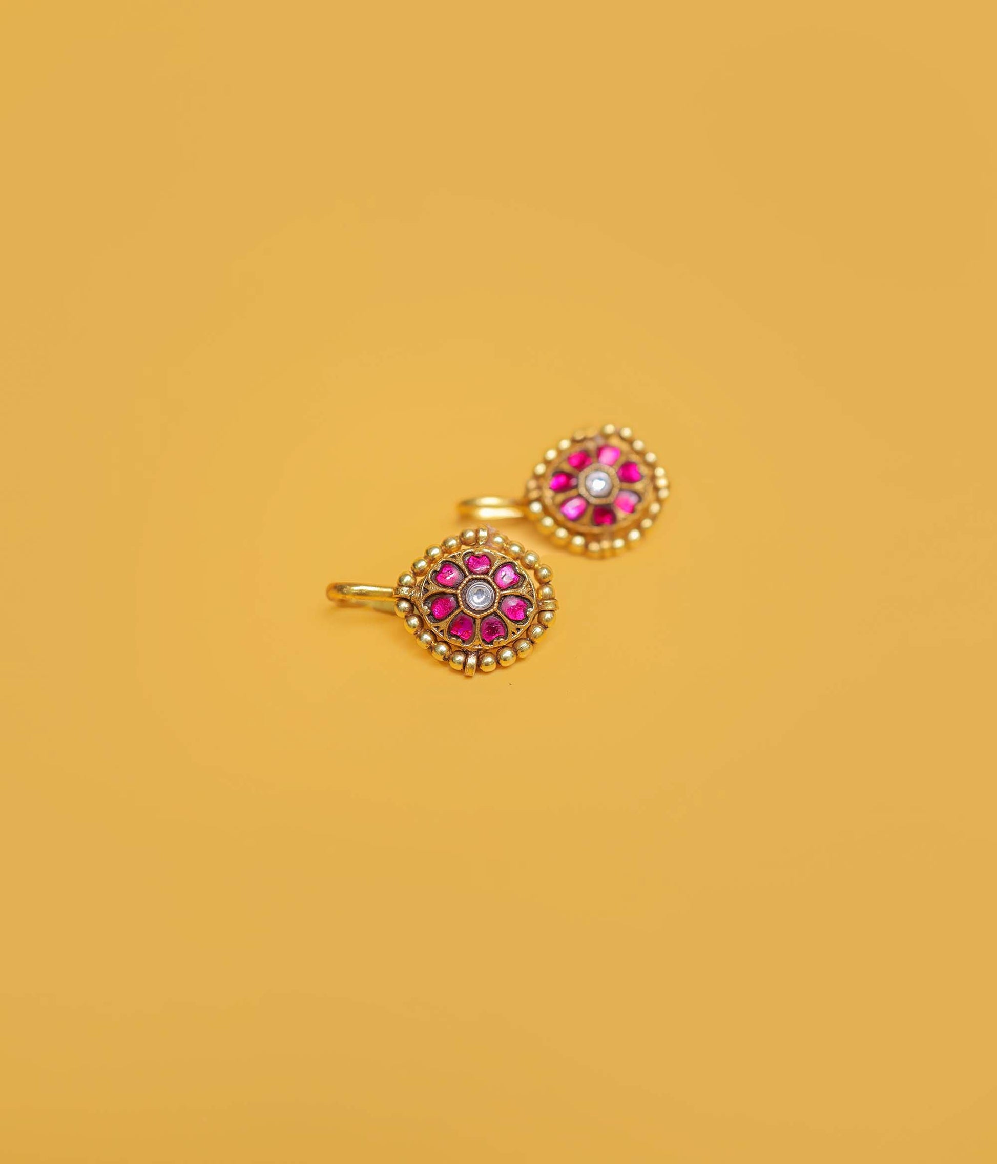 Ruby floral gold plated bugadi in 92.5 sterling silver with a beaded border and white centre stone.
