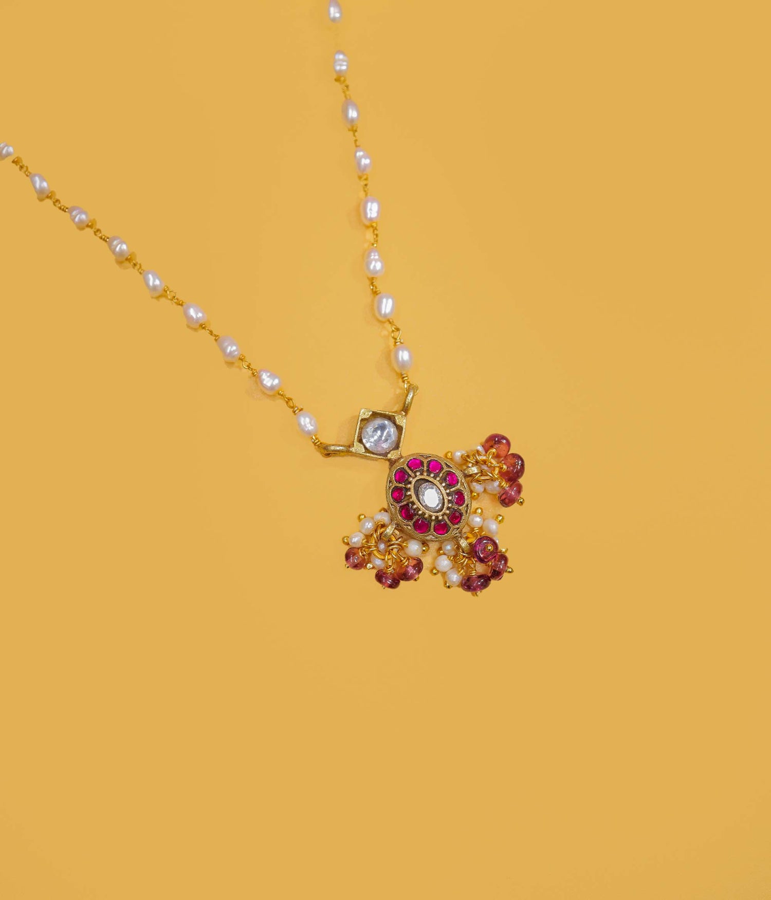 Gold plated pearl beaded necklace with a ruby-toned pendant and pearl clusters in 92.5 sterling silver.