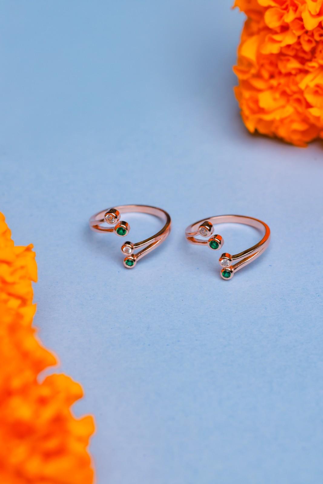 Rose gold adjustable toe rings with green and white stones.