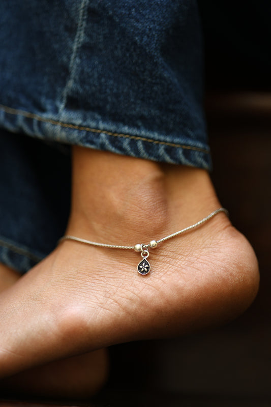Minimalist sterling silver anklet with small teardrop floral charm.