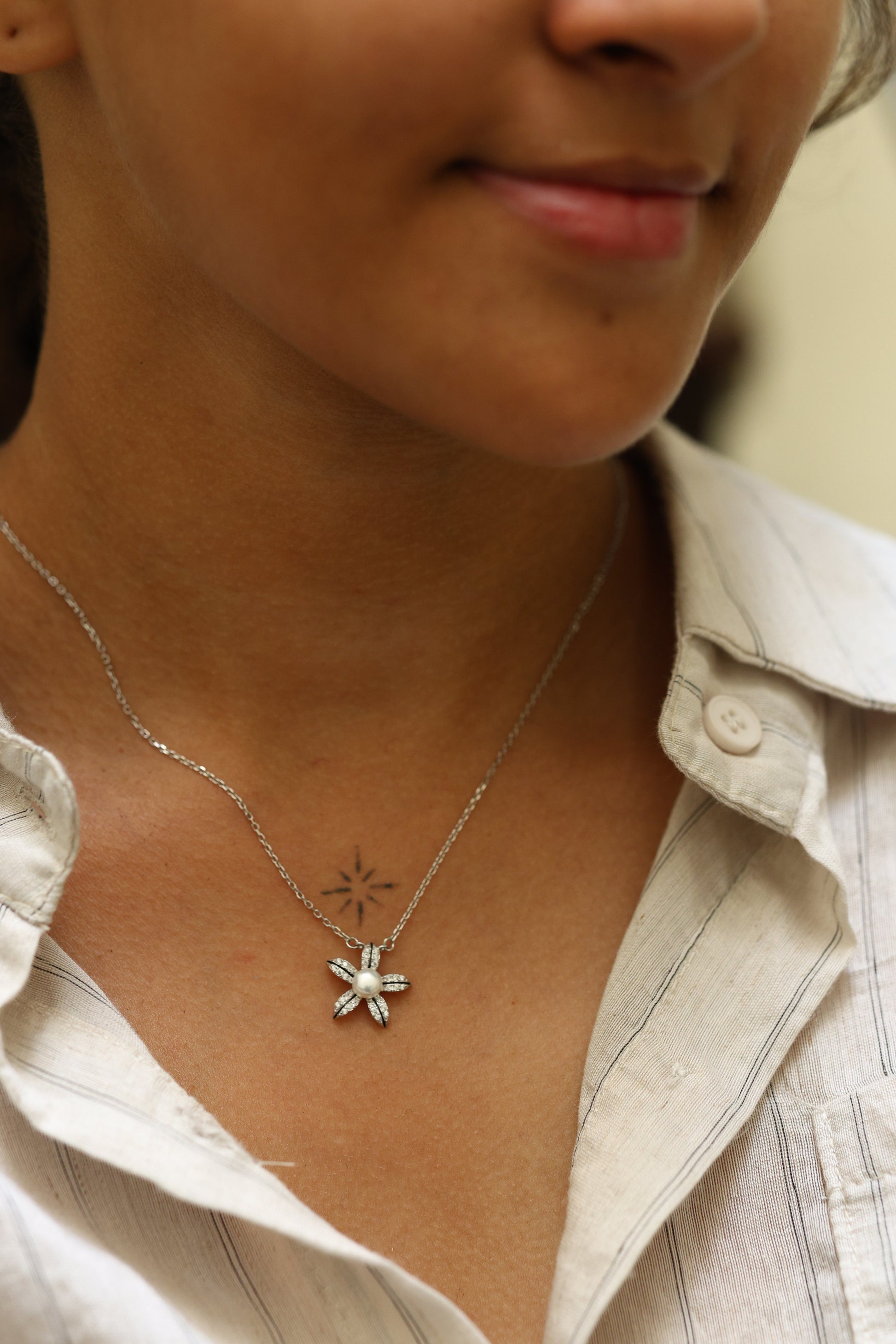Woman wearing a 92.5 sterling silver floral pendant necklace with pearl center and cubic zirconia petal accents.