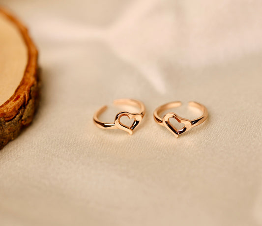 Pair of rose gold adjustable toe rings with open heart design.