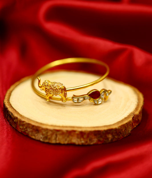 Gold bracelet with a unique design on a wooden slice against a red fabric background