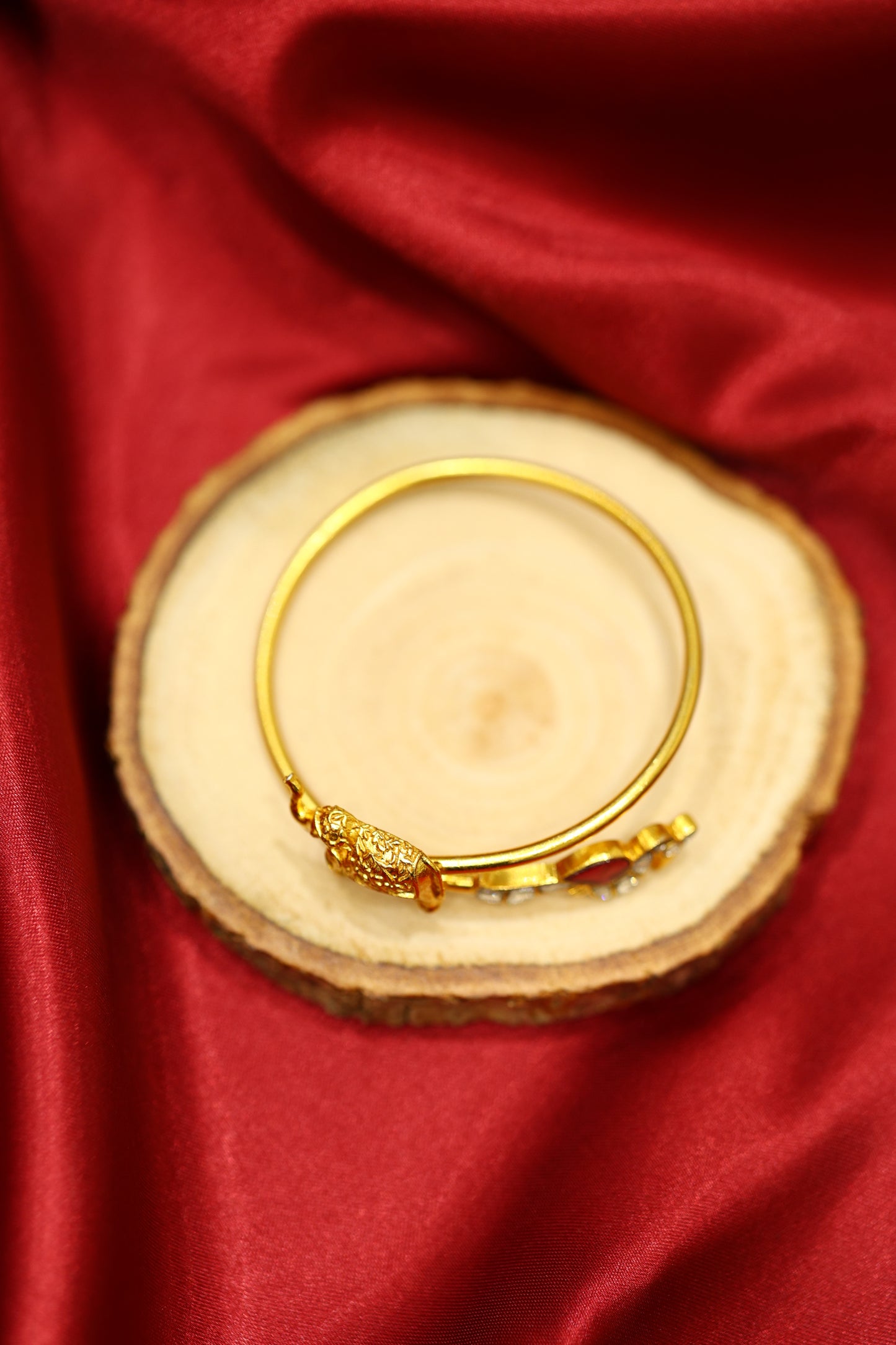 Golden elephant motif kada with ruby and kundan stones .
