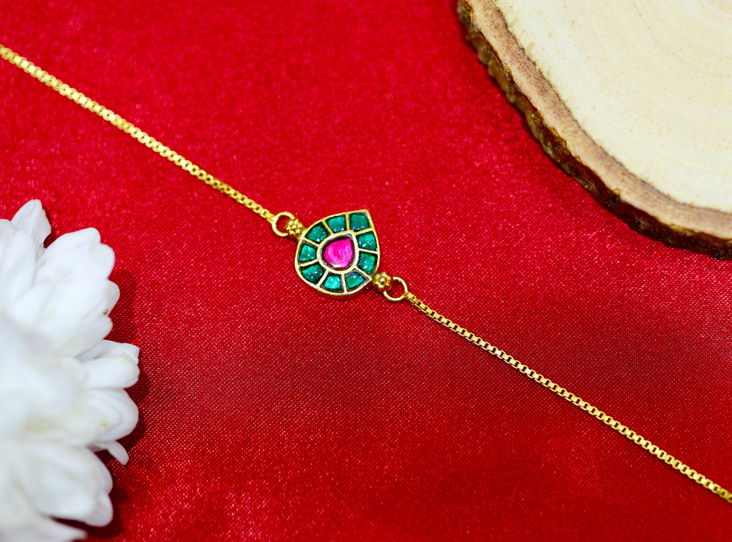 Gold bracelet with teardrop design featuring pink and green stones