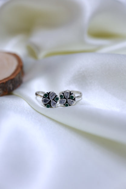 Pair of antique style silver toe rings with Kundan petal design and green stone accents.