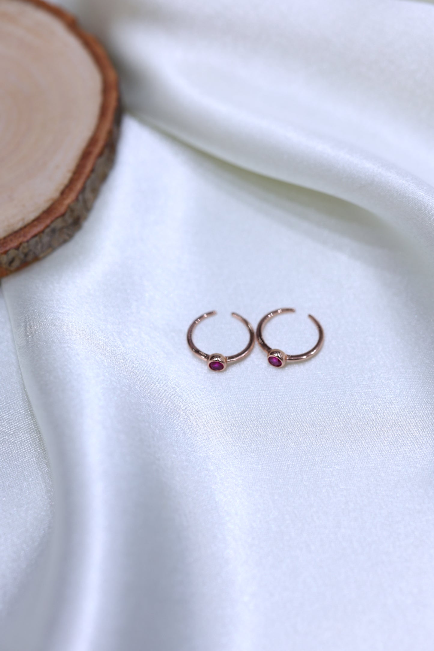 Pair of rose gold toe rings with ruby-colored stones .