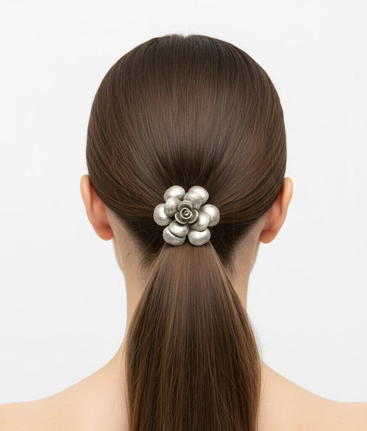 Woman with a high ponytail wearing a decorative hair clip on a plain background