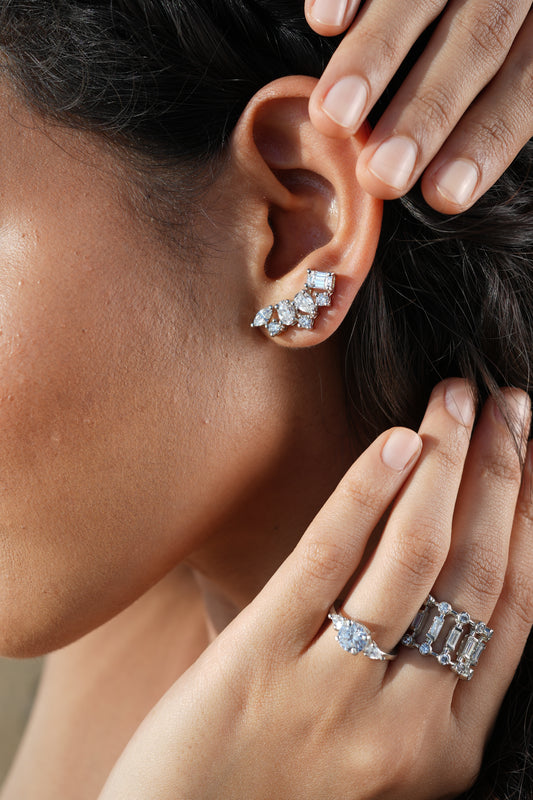 Hand holding a pair of sterling silver earrings set with cubic zirconia stones
