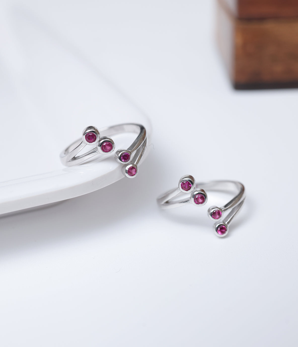 92.5 sterling silver toe ring with four round ruby-toned stones in an open design.