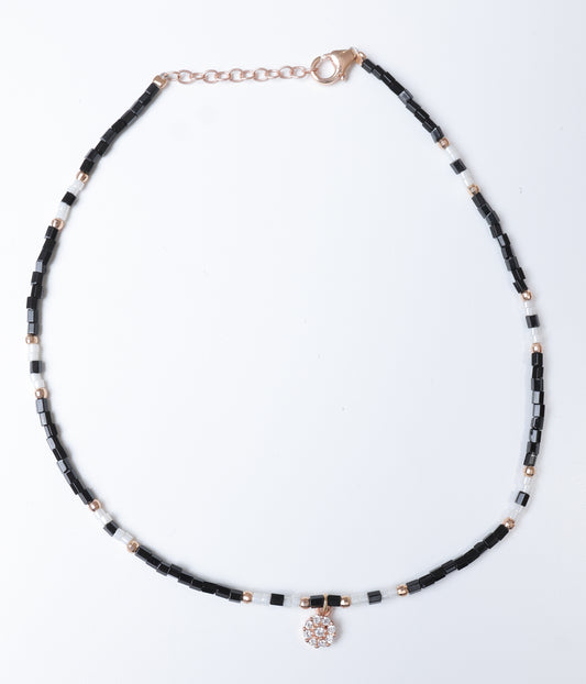 Black and white beaded anklet with rose gold-tone accents and a sparkling floral crystal charm.