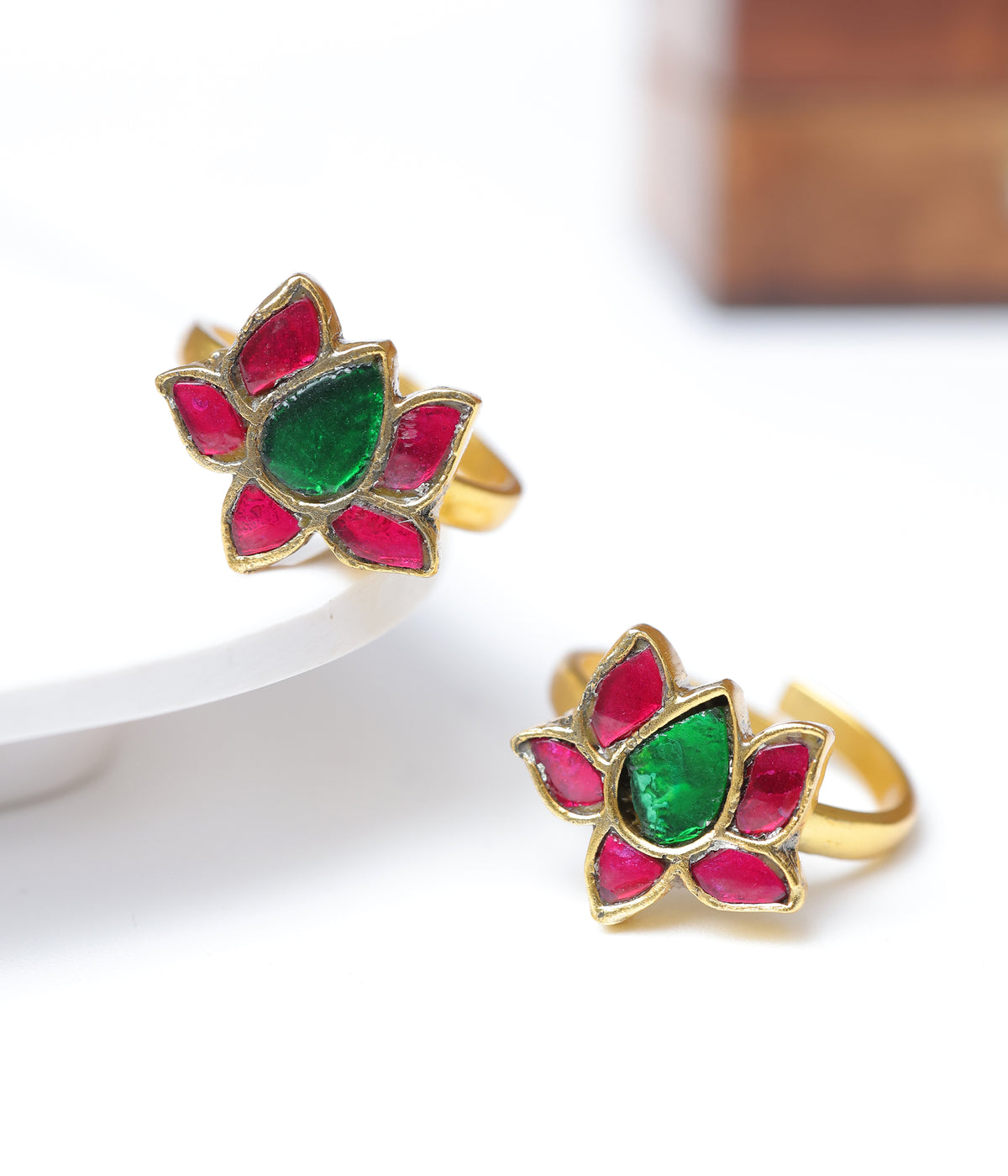 Gold-plated lotus toe ring with ruby-red petals and emerald-green centre stone.