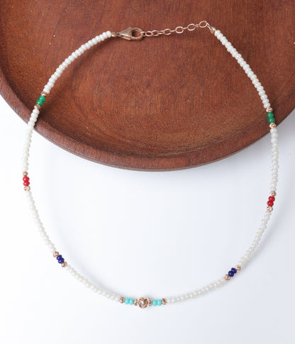 White pearl beaded anklet with multicolour green, red, blue and turquoise beads and rose gold-tone accents.