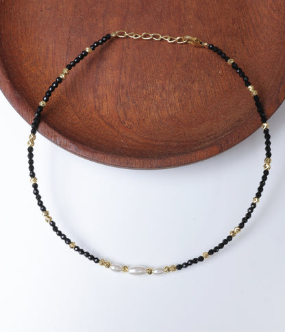 Black faceted bead anklet with white pearl accents and gold-tone decorative beads.